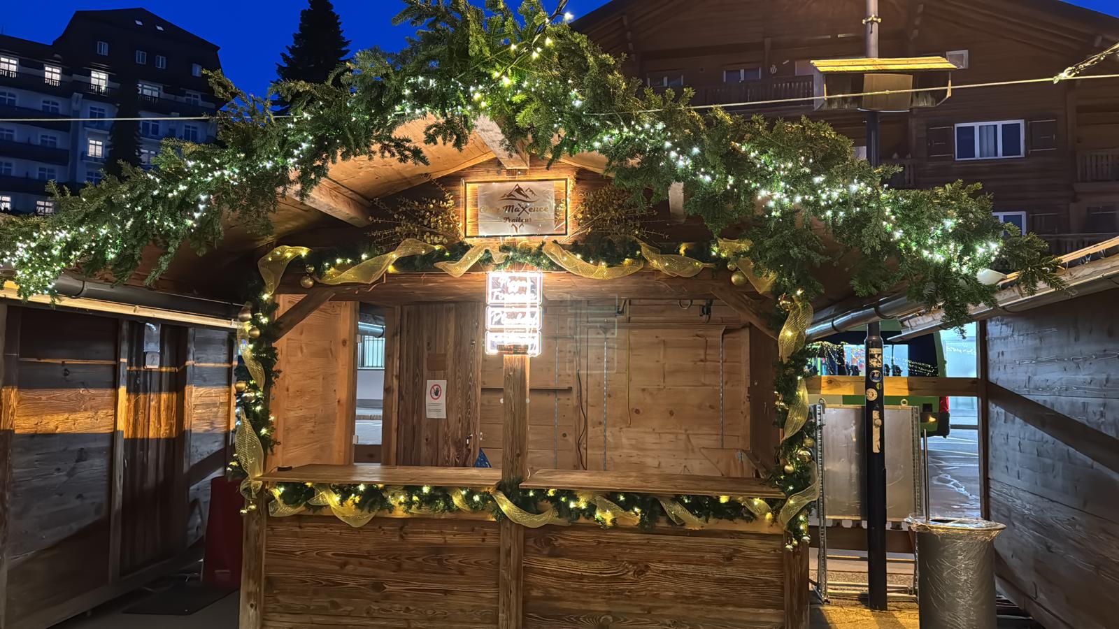 Outdoor chalet decorated at night with lights and fir branches